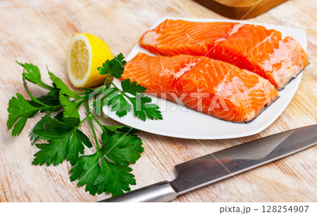 Raw salmon fillet with lemon and greens before cooking 128254907