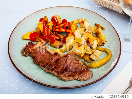 Veal steak with grilled potato and artichokes 128254916