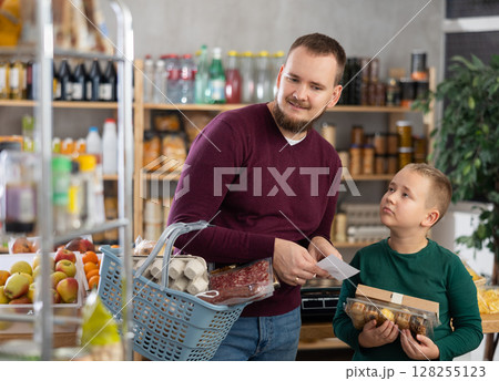 Young man with son buying groceries from shopping list 128255123