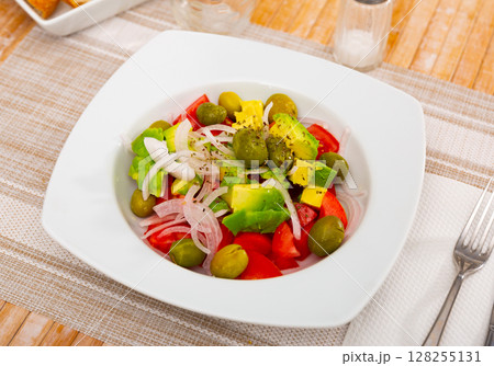 Avocado, tomato, olive, onion, salad on plate 128255131