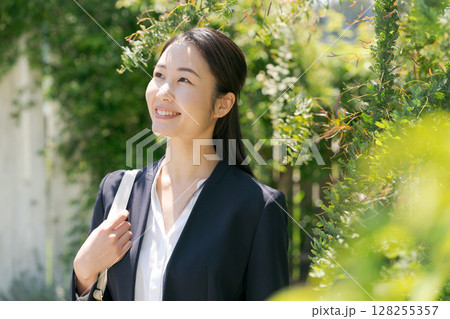 白い塀の前にいるスーツの女性 128255357