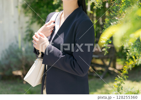 白い塀の前にいるスーツの女性 白い塀の前にいるスーツの女性 128255360