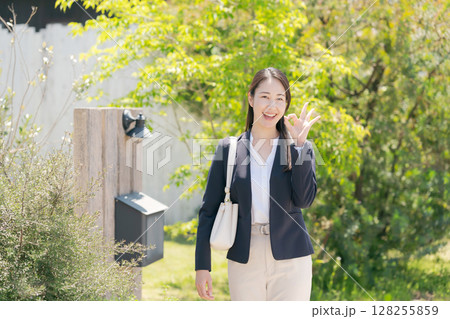 家の表札の前に立つ女性 128255859