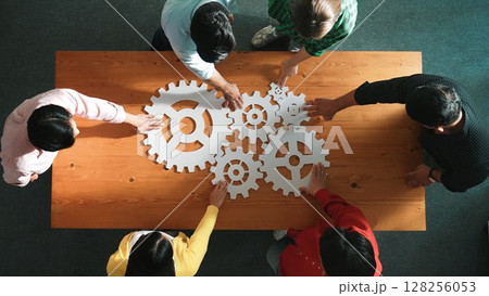 Top view of business people gathering white gear together at table. Convocation. 128256053
