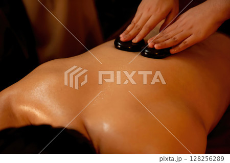 Hot stone massage at spa salon in luxury resort with warm candle light.Quiescent Hot stone massage at spa salon in luxury resort with warm candle light.Quiescent 128256289