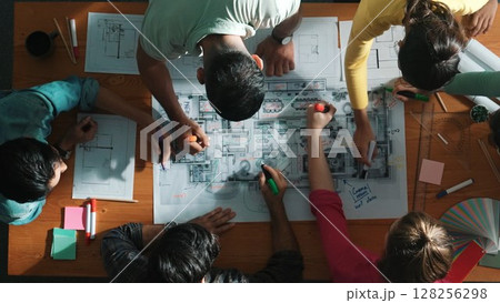Top down view of engineer team writing at blueprint at meeting table. Symposium. 128256298