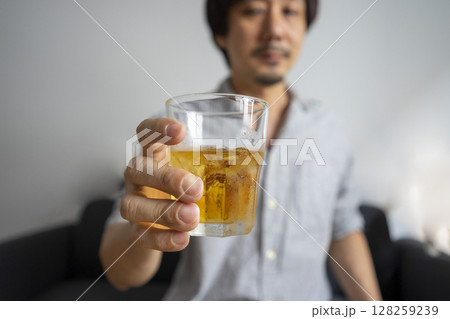 Alcoholism, depressed asian young man pouring, holding bottle whiskey into the glass, drinking alcohol beverage at night. Alcoholism, depressed asian young man pouring, holding bottle whiskey into the glass, drinking alcohol beverage at night. 128259239