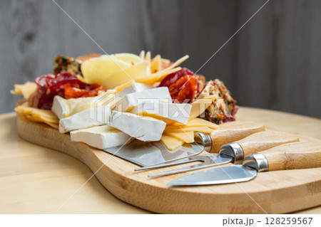 Food trend gift aperitivo party idea. Appetizers wooden grazing board with different antipasti charcuterie snacks and cheese. Assorted cheese meat platter. Disordered eating Food trend gift aperitivo party idea. Appetizers wooden grazing board with different antipasti charcuterie snacks and cheese. Assorted cheese meat platter. Disordered eating 128259567