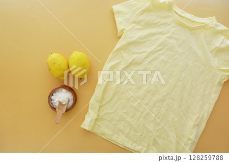 Baking soda, lemon and a shirt on yellow background Baking soda, lemon and a shirt on yellow background 128259788