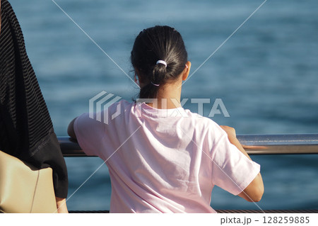 Girl enjoying a view of the sea at a coastal location 128259885