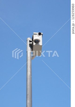 Security camera mounted on pole against clear blue sky Security camera mounted on pole against clear blue sky 128259960