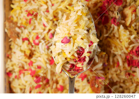 Colorful biryani served in a large spoon with rose petals Colorful biryani served in a large spoon with rose petals 128260047