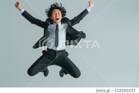 スーツを着た男性がジャンプをしている スーツを着た男性がジャンプをしている 128260235