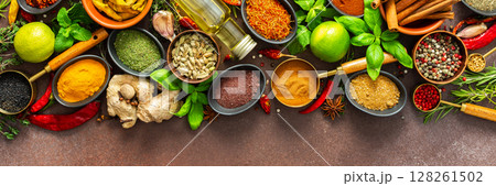 A rich palette of colorful spices and herbs, resting on a brown background, radiating freshness and an inviting aroma, perfect for gourmet inspiration, banner 128261502