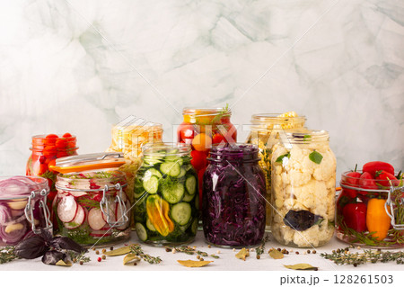 A variety of fresh vegetables cabbage, tomatoes, cucumbers and radishes, onions, corn, peppers and cauliflower, undergoing fermentation for a nutritious and probiotic-rich food source A variety of fresh vegetables cabbage, tomatoes, cucumbers and radishes, onions, corn, peppers and cauliflower, undergoing fermentation for a nutritious and probiotic-rich food source 128261503