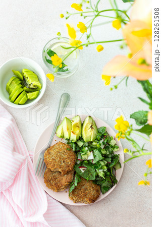 Quinoa cutlets and mixed salad with avocado and radishes, kiwi and water 128261508
