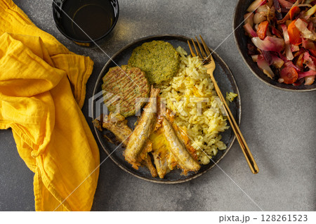 A savory, balanced breakfast with turmeric rice, baked ocean fish, broccoli pancakes, and roasted vegetable salad, providing essential proteins and healthy fats for an energizing start 128261523