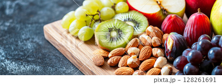 Freshly prepared breakfast board featuring assorted fruits and nuts served on a wooden platter 128261691