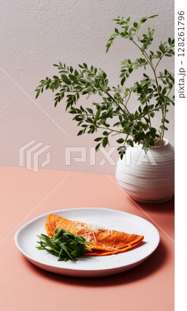 A delicious seasonal breakfast showcases a golden omelet served with fresh greens, accompanied by simple tableware and an earthy vase with foliage 128261796