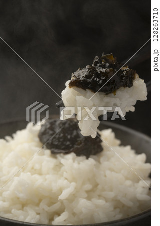 海苔の佃煮を乗せた炊きたてのご飯を箸で持ち上げる 128263710