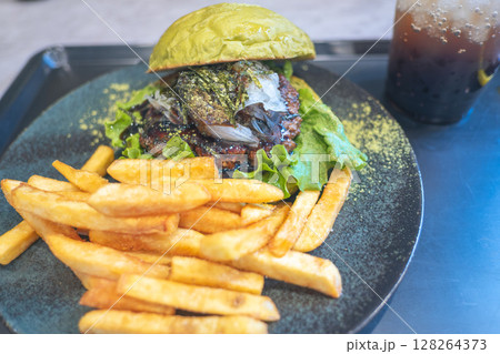Gourmet burger with fries and a drink on a stylish plate. 128264373