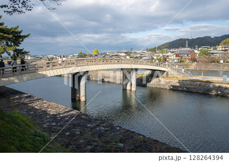 Bridge over a river with cloudy sky and scenic surroundings. 128264394