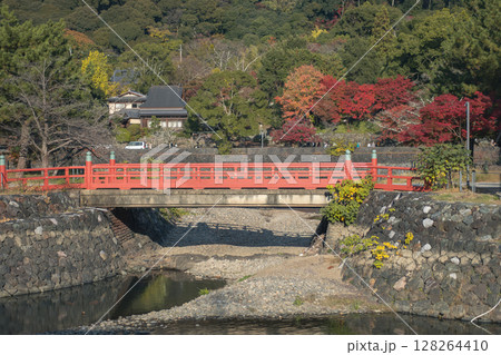 Kisen Bridge, Uji, Kyoto, Japan surrounded by vibrant foliage and calm water. 128264410