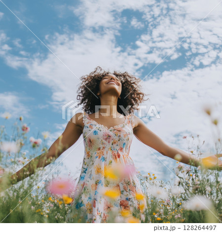 Woman with open arms in a serene wildflower meadow 128264497
