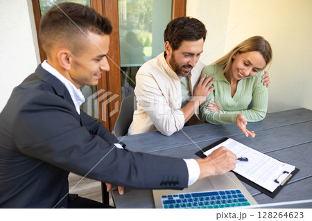Couple reviewing property plans with realtor on outdoor table Couple reviewing property plans with realtor on outdoor table 128264623