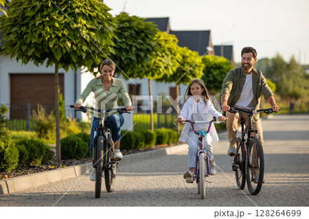 Family bike outing on residential path with trees and homes 128264699
