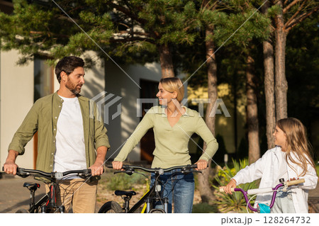 Family with bikes preparing for ride outside modern house garage Family with bikes preparing for ride outside modern house garage 128264732