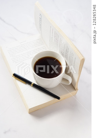 ペーパーバック(洋書)とコーヒーの入ったコーヒーカップで、コーヒーを飲みながら読書中のイメージ ペーパーバック(洋書)とコーヒーの入ったコーヒーカップで、コーヒーを飲みながら読書中のイメージ 128265348