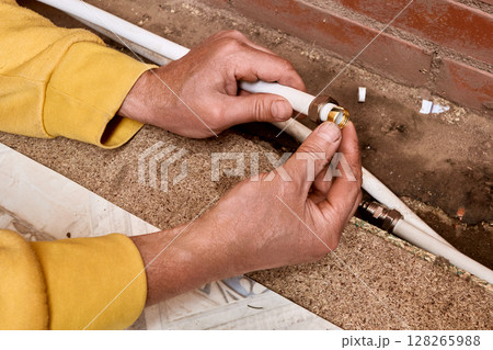 Installation process shows technician fitting compression ring to composite tubing before connecting water supply lines using compression fitting for plumbing work. Installation process shows technician fitting compression ring to composite tubing before connecting water supply lines using compression fitting for plumbing work. 128265988