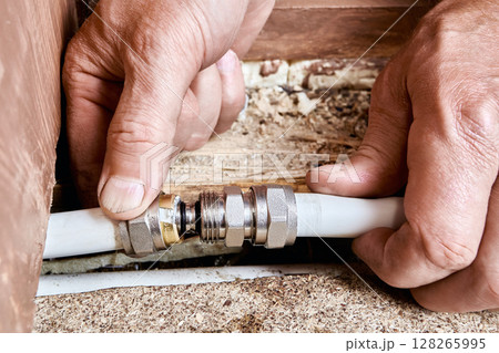 Plumber installs compression coupling to connect two sections of multilayer pipe previously cut at point of damage caused by internal pipe rupture. 128265995