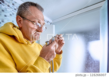 Plumber places sealing ring inside metal nut on flexible hose, ensuring leak-free joint before attaching shower hose in enclosed shower area. 128266007
