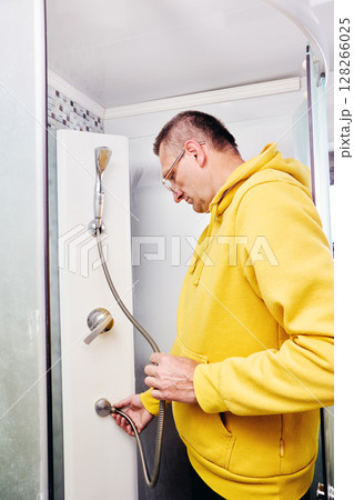 Homeowner repairs flexible shower head-in walk in shower. 128266025