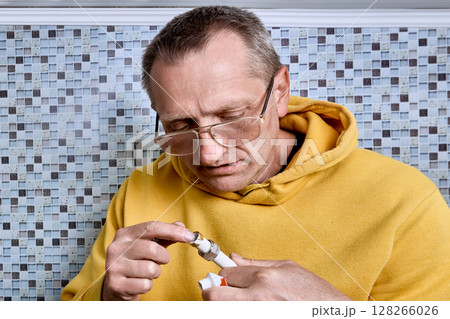 Plumber applies plumbing paste to pipe end to ease insertion of internal support while compression ring of compression coupling is already in place. 128266026