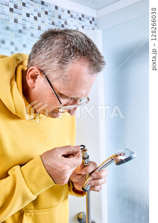 Preparing for hose replacement plumber checks sealing washer at end of shower hose due to leak in old shower connection. 128266038