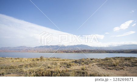 the lake of  Issyk kul  and the wide meadow in kyrgyzstan with the tian shan mountain range background 128269871