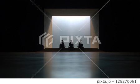 Yoga and meditation class indoor, Silhouettes of three figures meditating in a dimly lit space. 128270061