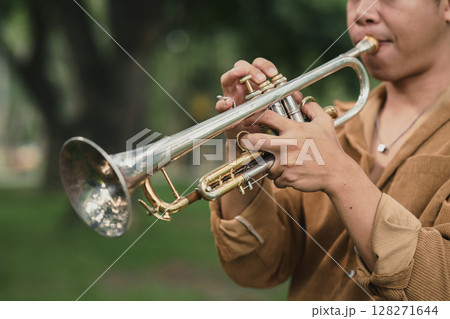 Male trumpet player performing solo in a peaceful green park Male trumpet player performing solo in a peaceful green park 128271644