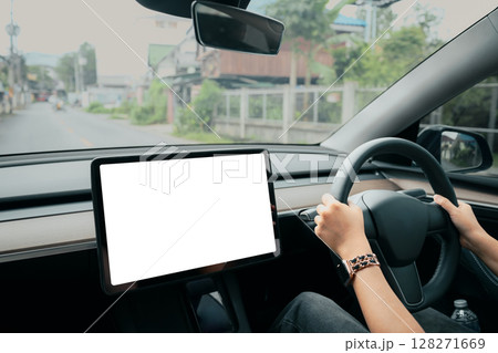 Person driving an electric car with a blank dashboard touchscreen in a modern vehicle interior 128271669