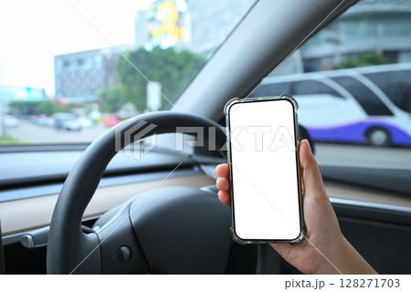 Hands using a mobile phone behind the wheel in a modern electric vehicle interior 128271703