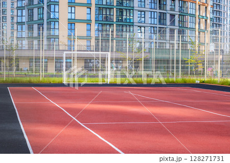 A tennis court placed prominently with a building in the background 128271731