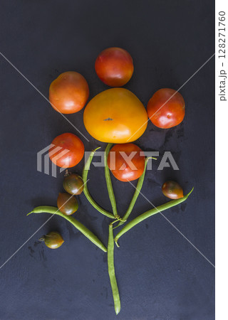Fresh raw vegetables: tomatoes, green beans as flower on a black background Fresh raw vegetables: tomatoes, green beans as flower on a black background 128271760