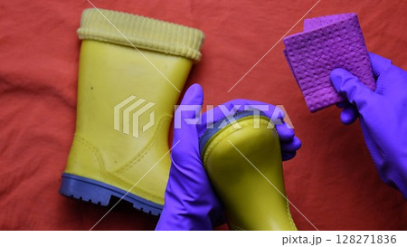 Hands in purple rubber gloves clean kids yellow rubber boots Hands in purple rubber gloves clean kids yellow rubber boots 128271836