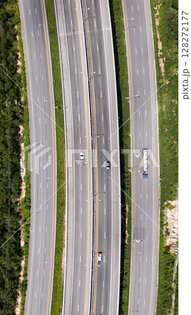 Drone shot aerial view multiple highway lanes in Thailand with few vehicles. Clean asphalt, green roadside, and minimal traffic convey efficiency and motion 128272177