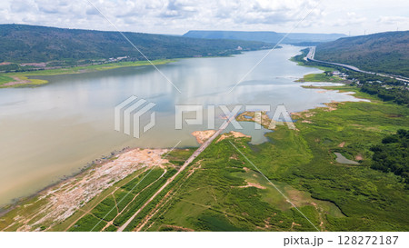 A wide aerial shot of Lam Takhong reservoir surrounded by hills and greenery in Nakhon Ratchasima. The scenic water source blends nature, infrastructure, and regional beauty A wide aerial shot of Lam Takhong reservoir surrounded by hills and greenery in Nakhon Ratchasima. The scenic water source blends nature, infrastructure, and regional beauty 128272187