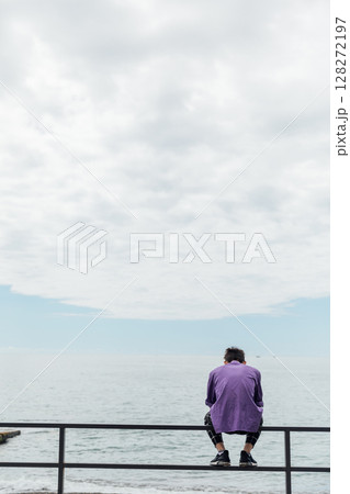 Man sitting on the beach and looking at the sea Man sitting on the beach and looking at the sea 128272197