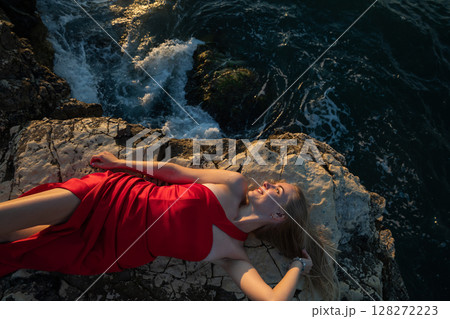 Blonde woman in red dress on a rock Blonde woman in red dress on a rock 128272223
